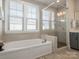 Modern bathroom boasting a soaking tub, glass-enclosed shower, and large window at 5078 Hyannis Ct, Matthews, NC 28104