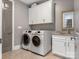 Well-equipped laundry room with a front load washer and dryer, granite countertops, and storage cabinets at 5078 Hyannis Ct, Matthews, NC 28104