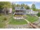 Stunning lakefront home featuring multiple balconies, stone patio with seating and lush landscaping at 602 Shoreline Rd # 144, New London, NC 28127