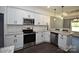 Well-lit kitchen featuring stainless steel appliances, granite countertops, white cabinets, and dark hardwood floors at 6519 Pargo Rd, Charlotte, NC 28216