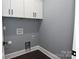 Laundry room featuring gray walls, white cabinets, black hardware, and dark laminate flooring at 6519 Pargo Rd, Charlotte, NC 28216