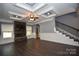 Open living room featuring dark wood floors, tray ceiling, fireplace with stone surround, and staircase at 6519 Pargo Rd, Charlotte, NC 28216