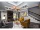 Staged living room featuring dark wood floors, tray ceiling, fireplace with stone surround, and staircase at 6519 Pargo Rd, Charlotte, NC 28216