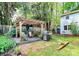 Landscaped backyard featuring a pergola, patio, grill, and lush garden beds at 7020 Leesburg Rd, Charlotte, NC 28215
