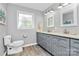 Bathroom showcasing a double vanity, wood-look tile floor, a toilet, and a bright window at 7020 Leesburg Rd, Charlotte, NC 28215