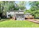 A full view of the back exterior showcasing a large lawn, a screened-in porch, and a wood deck at 7020 Leesburg Rd, Charlotte, NC 28215