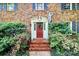 Charming brick home featuring a red front door, decorative wreath, and manicured shrubs at 7020 Leesburg Rd, Charlotte, NC 28215