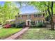 Charming brick home featuring lush landscaping, a manicured lawn, and a welcoming red front door at 7020 Leesburg Rd, Charlotte, NC 28215