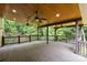 Spacious covered deck surrounded by lush trees, featuring wood flooring, ceiling fans, and ample seating space at 7067 Rocky Falls Rd, Charlotte, NC 28211