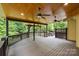 Expansive covered deck featuring ceiling fans, wood flooring, and tranquil views of the surrounding greenery at 7067 Rocky Falls Rd, Charlotte, NC 28211