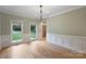 Elegant dining room with wainscoting and natural light, complemented by hardwood floors and views to the front yard at 7067 Rocky Falls Rd, Charlotte, NC 28211