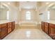 Bright bathroom featuring a soaking tub, a window, and dual wooden vanities at 709 Circle Trace Rd, Monroe, NC 28110