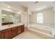 Bright bathroom featuring a soaking tub, dual wooden vanities, and natural light at 709 Circle Trace Rd, Monroe, NC 28110