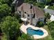Expansive aerial view of a grand home surrounded by lush greenery and a sparkling private pool at 7409 Stonecroft Park Dr, Charlotte, NC 28226