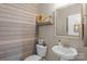 Cozy half bathroom with wood paneled walls, pedestal sink and decorative mirror at 7693 Lazy Hollow Ln, Denver, NC 28037