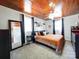 Bedroom with a wood plank ceiling, grey walls, carpet floors, and a large bed with an orange comforter at 8475 Nc 49 N Hwy, Mount Pleasant, NC 28124
