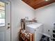 Bright laundry area with wood plank ceiling, modern washer and dryer, handy shelving for detergent, and shoe rack for storage at 8475 Nc 49 N Hwy, Mount Pleasant, NC 28124