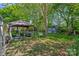 Lush backyard featuring a gazebo, swing, storage shed, and mature trees for ample shade at 8651 Walsham Dr, Charlotte, NC 28277