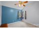 Bedroom featuring a bold blue wall, fan, neutral carpet, and natural light from two windows at 8651 Walsham Dr, Charlotte, NC 28277
