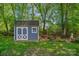 Cozy outbuilding with double doors surrounded by green lawn, trees, and a charming fire pit area at 8651 Walsham Dr, Charlotte, NC 28277