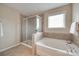 Bathroom with glass enclosed shower, soaking tub with faucet, and a window at 985 Angelica Ln, Tega Cay, SC 29708