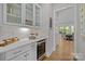 Elegant bar area features glass-front cabinets, a wine cooler, quartz countertops, and stylish tile backsplash at 1052 Harlow'S Crossing Dr, Weddington, NC 28104