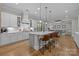 White kitchen with a large island, stainless steel appliances, and hardwood floors, open to the living area at 1052 Harlow'S Crossing Dr, Weddington, NC 28104