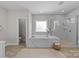 Luxurious main bathroom featuring a soaking tub, separate shower, and elegant marble tile at 1052 Harlow'S Crossing Dr, Weddington, NC 28104