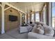 Bright sunroom with large, comfortable sectional sofa, brick accent wall with mounted tv, and light gray color palette at 1052 Harlow'S Crossing Dr, Weddington, NC 28104