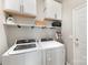 Bright laundry room featuring modern washer and dryer with overhead shelving for convenient storage at 1313 Loggerhead Dr, Lancaster, SC 29720