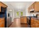 A bright kitchen featuring wooden cabinets, a stainless steel refrigerator, and natural light from adjacent dining area at 1325 Red Oaks Dr, Rock Hill, SC 29730
