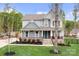 Charming gray home with a covered porch, stone accents, lush landscaping, and a well-maintained lawn at 137 Brawley Woods Ln, Mooresville, NC 28115