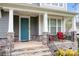 Inviting front porch with stone columns, seating area, and a vibrant blue front door at 137 Brawley Woods Ln, Mooresville, NC 28115