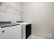Bright laundry area featuring a modern white washer and dryer plus wire shelving for storage convenience at 137 Brawley Woods Ln, Mooresville, NC 28115