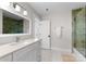 Bright bathroom with a vanity, framed mirror, and a glass-enclosed shower-tub combination at 1751 Merriman Ave, Charlotte, NC 28203