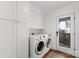 A bright and functional laundry room with white cabinetry, modern washer and dryer, and wood-look floors at 1751 Merriman Ave, Charlotte, NC 28203