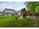 Spacious backyard with a wooden playset, swing set, and lush green grass; perfect for outdoor Gathering fun and recreation at 2012 Galty Ln, Charlotte, NC 28270