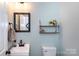 Clean bathroom with a modern vanity, sleek mirror, neutral color palette and a decorative shelf with towels at 2012 Galty Ln, Charlotte, NC 28270