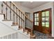 Elegant entryway featuring a wooden staircase with wrought iron railings and a view of the wooden front door at 218 Kimrod Ln, Charlotte, NC 28270
