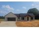Single-story home with black roof, white siding, an attached garage, and professional landscaping at 28647 Nc Hwy 73 Hwy, Albemarle, NC 28001