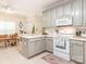 Bright kitchen features gray cabinets, white appliances, and a cozy dining area with tile floors at 3033 Beech Ct, Indian Trail, NC 28079