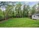 Lush green backyard features mature trees, a storage shed, and a fence at 312 Peach St, Shelby, NC 28150