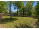 Large, grassy backyard surrounded by a wooden fence and mature trees provides ample space for outdoor activities at 3423 Sudbury Rd, Charlotte, NC 28205