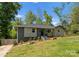 Charming single-story home with gray painted brick and siding, black front door, landscaped yard, and inviting curb appeal at 3423 Sudbury Rd, Charlotte, NC 28205