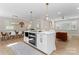 Open concept kitchen with a white kitchen island, stainless steel appliances, hardwood floors, and modern pendant lighting at 3423 Sudbury Rd, Charlotte, NC 28205