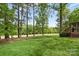 A backyard with a wooden deck, manicured lawn, and views of towering trees and greenery at 3764 Glenn Oaks Dr, Maiden, NC 28650
