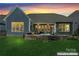 Backyard view showcasing a covered patio, outdoor kitchen, stone firepit, and lush green lawn at dusk at 4012 Brandywine Ter, Lancaster, SC 29720