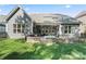 Backyard view showcasing a covered patio, outdoor kitchen, stone firepit, and lush green lawn at 4012 Brandywine Ter, Lancaster, SC 29720