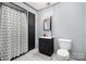Simple bathroom featuring a white toilet, black vanity with a mirror, and a shower with a curtain at 4517 Lake Shore N Rd, Denver, NC 28037