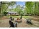 Backyard stone fire pit with Adirondack chairs and green yard for relaxation and entertaining at 4517 Lake Shore N Rd, Denver, NC 28037